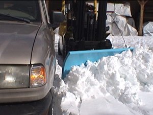 Plowing snow next to a silver car