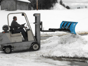 Man plowing snow using silver forklift